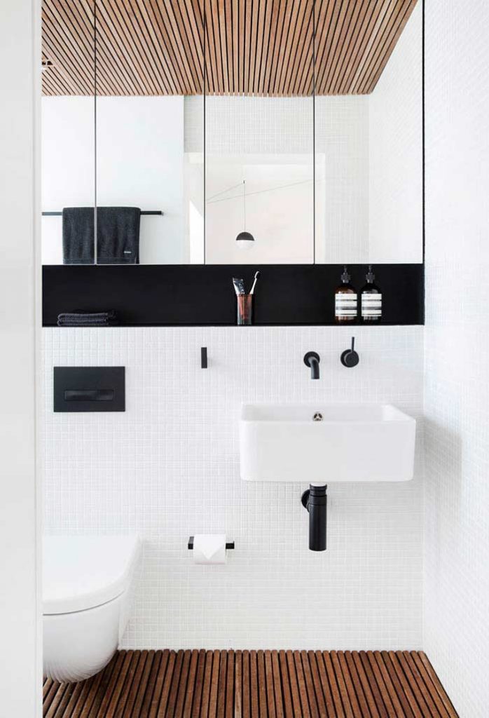 Um banheiro preto e branco que acompanha as tendências: pastilhas brancas, madeira no teto e no piso, assim como louça preta escovada