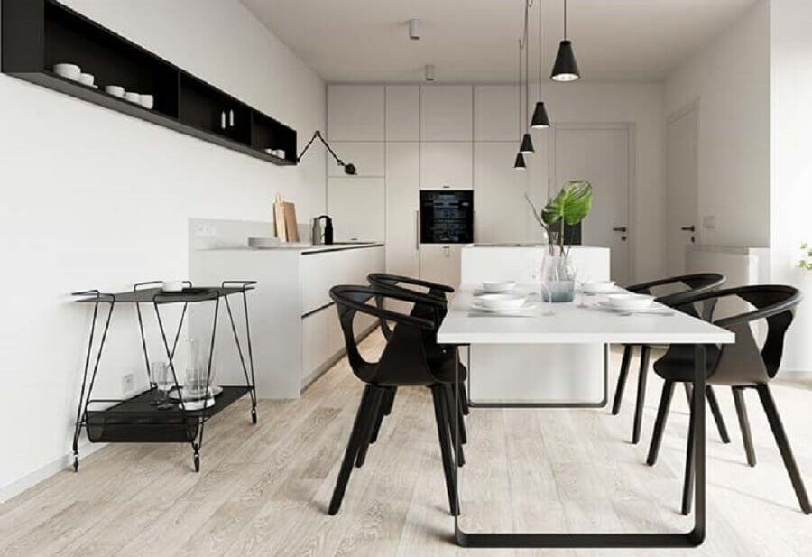 Decoração moderna para cozinha planejada preta e branca bem ampla com mesa acoplada à ilha e piso de madeira 