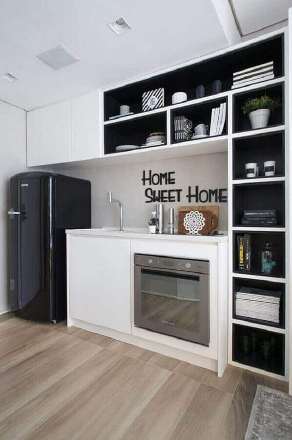 Cozinha preta e branca simples decorada com vários nichos e piso de madeira